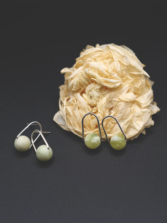 Pair of earrings with green beads on a dark background